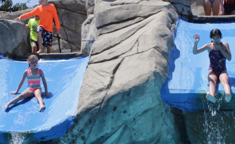 Two children riding on separate water slides