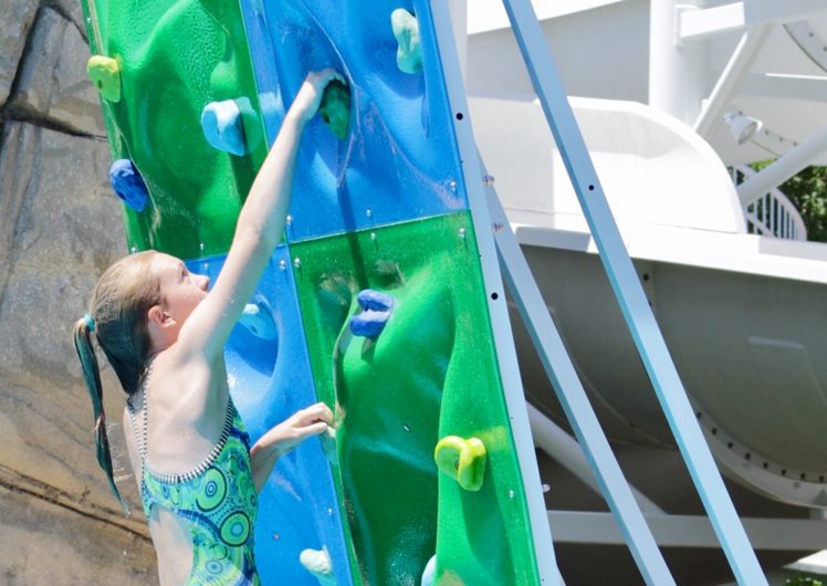 Girl climbing rock wall in water